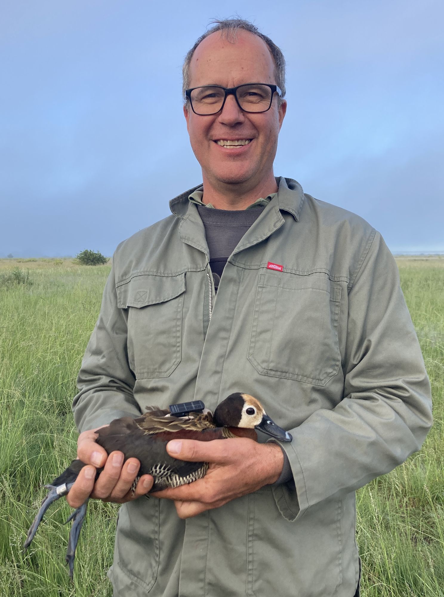 Pieter du Plessis holding a duck in a grassland